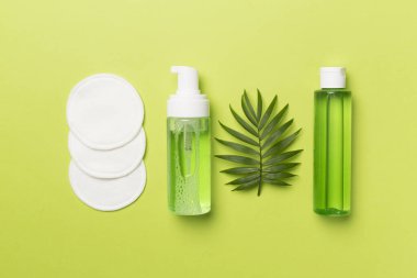 Renkli arka planda köpüklü yüz temizleyici ve mikiler suyu, üst görünüm