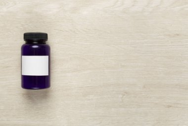 Ahşap zemin üzerinde vitaminler olan plastik şişe.