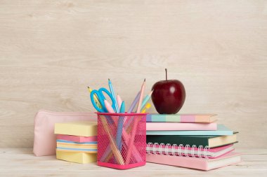 Ahşap masa üzerinde kitap ve kırtasiye malzemesi olan kompozisyon. Okul konseptine dönelim.