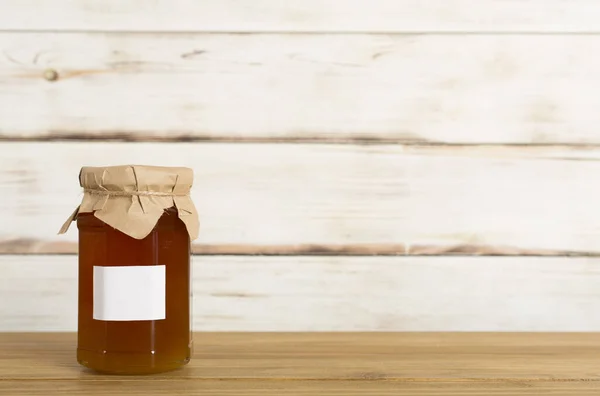 Jar with honey on wooden table. Mock up design