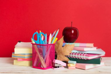 Ahşap masa üzerinde kitap ve kırtasiye malzemesi olan kompozisyon. Okul konseptine dönelim.