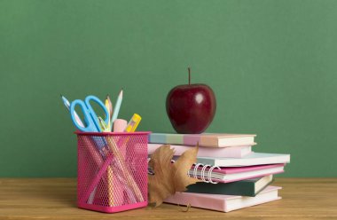 Ahşap masa üzerinde kitap ve kırtasiye malzemesi olan kompozisyon. Okul konseptine dönelim.