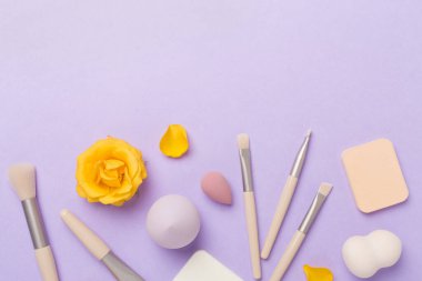 Renk arkaplanında makyaj fırçaları ve süngerler, üst görünüm