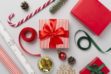 Kağıt kollu hediye kutuları ve renk arkaplanı üzerine noel süslemesi, üst görünüm
