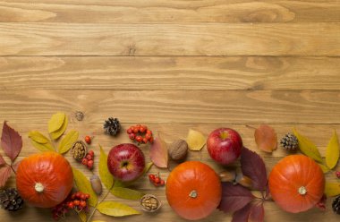 Tahta arka planda balkabakları, meyveler ve sonbahar yapraklarıyla yatıyordu.