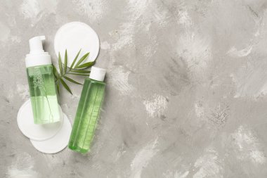 Köpüren yüz temizleyici ve beton arka planda eko pedleri olan mikiler suyu, üst görünüm.