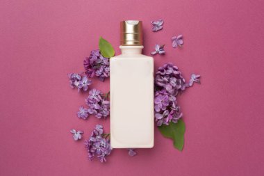 Renkli arka planda kozmetik şişesi ve çiçekli kompozisyon, üst görünüm