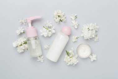 Renkli arka planda kozmetik şişeleri ve çiçekleri olan kompozisyon, üst görünüm