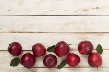 Ahşap zemin üzerinde yaprakları olan taze kırmızı elmalar, üst görünüm