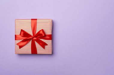 Renkli arka planda kırmızı kurdeleli hediye kutusu, üst görünüm.