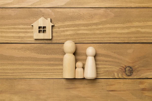 Wooden family figures with house on wooden background,top view