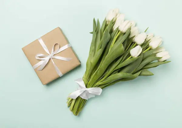 白いチューリップの花束とギフトボックスの色の背景 トップビュー — ストック写真
