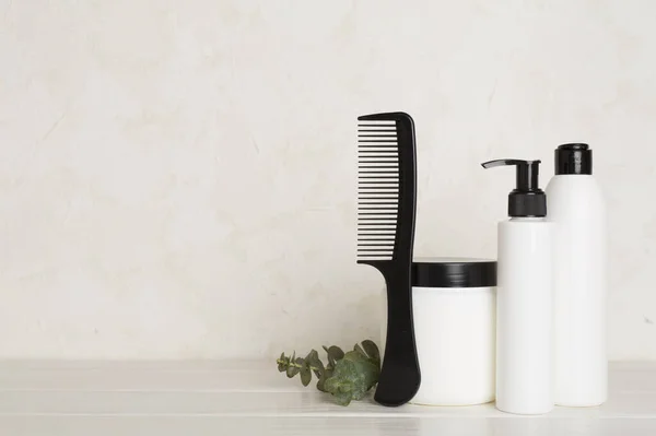 Professional hair care products with comb on wooden background
