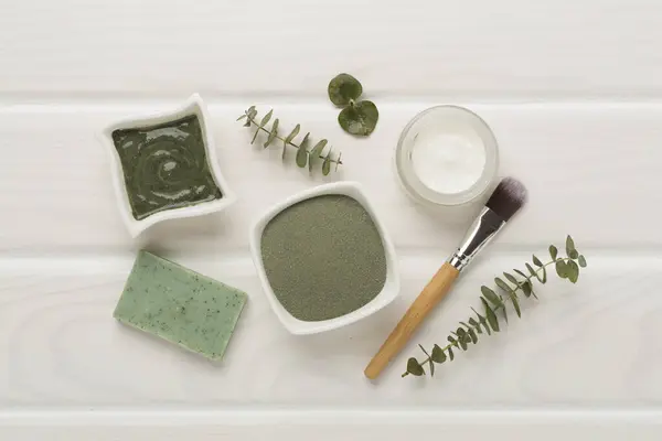 Composition with cosmetic clay and spa products on wooden background, top view
