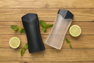 Ahşap arka planda nane yapraklı erkekler kozmetik şişeleri, üst manzara.