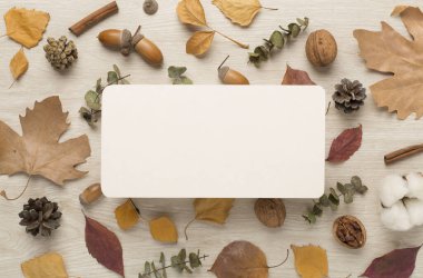Ahşap zemin üzerinde sonbahar yaprakları olan tebrik kartı modeli, üst görünüm