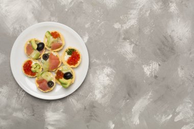 Somon balıklı tartlar ve beton arka planda havyar.