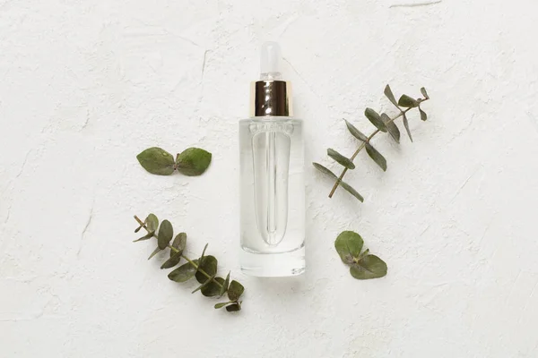 Herbal face serum on concrete background, top view