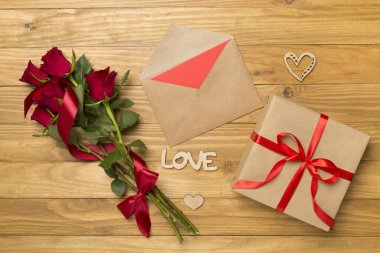 Sevgililer Günü hediye paketi. Ahşap arka planda kırmızı güller, üst manzara.