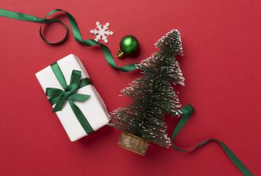 Arkaplanda hediye kutuları ve dekoru olan minyatür noel ağacı