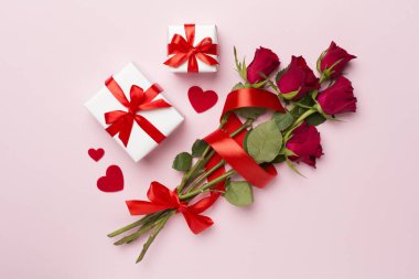 Valentines day gifts with red roses on color background, top view