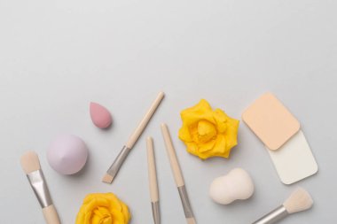 Renk arkaplanında makyaj fırçaları ve süngerler, üst görünüm