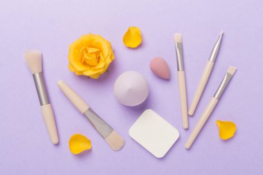 Renk arkaplanında makyaj fırçaları ve süngerler, üst görünüm