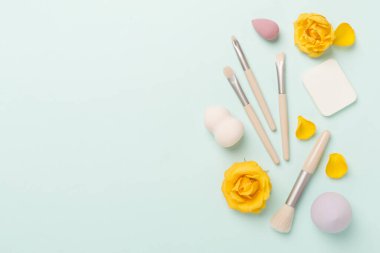 Renk arkaplanında makyaj fırçaları ve süngerler, üst görünüm