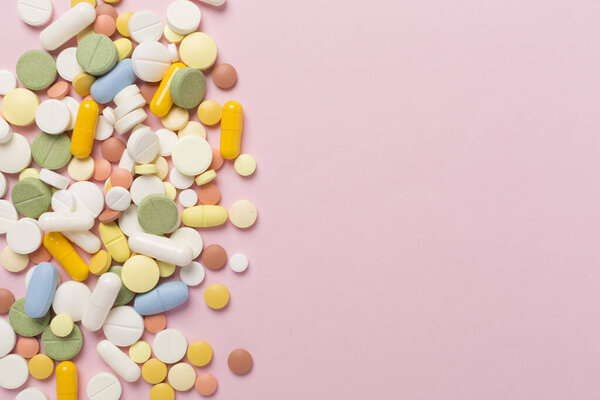 Различные медицинские таблетки и капсулы на цветном фоне, вид сверху