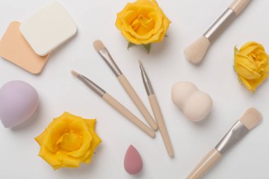 Renk arkaplanında makyaj fırçaları ve süngerler, üst görünüm