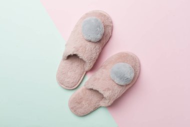 Soft pink slippers on color background, top view