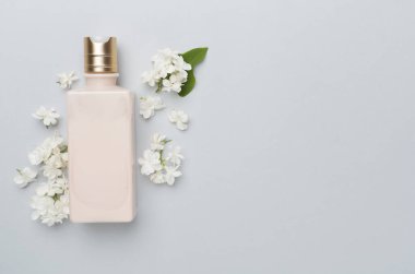 Renkli arka planda kozmetik şişesi ve çiçekli kompozisyon, üst görünüm