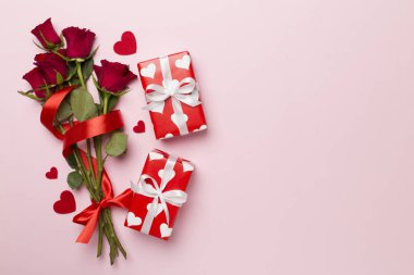 Valentines day gift box with red roses on color background, top view