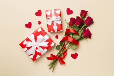 Valentines day gift box with red roses on color background, top view