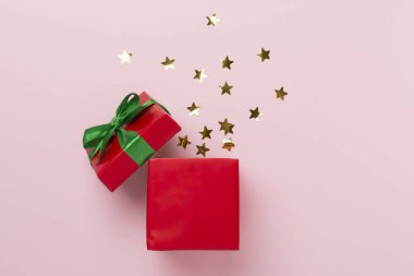 Renk arkaplanında parti konfetisi olan kırmızı hediye kutusunu aç, üst görünüm