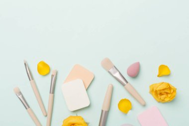 Renk arkaplanında makyaj fırçaları ve süngerler, üst görünüm