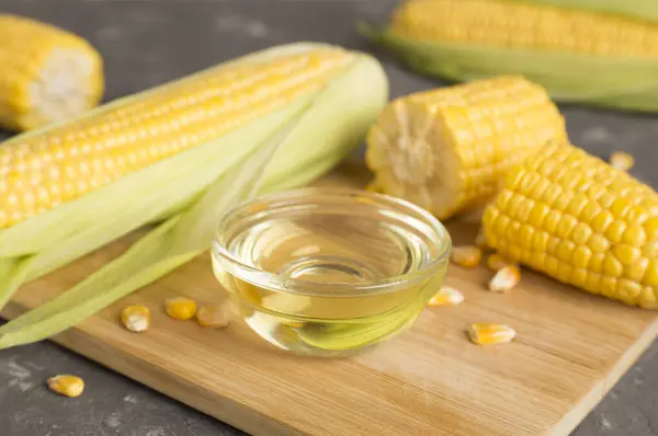Corn oil with fresh cobs on wooden table