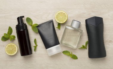 Ahşap arka planda nane yapraklı erkekler kozmetik şişeleri, üst manzara.