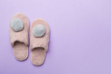 Soft pink slippers on color background, top view