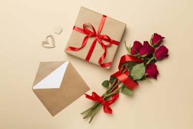 Valentines day gift box with red roses on color background, top view