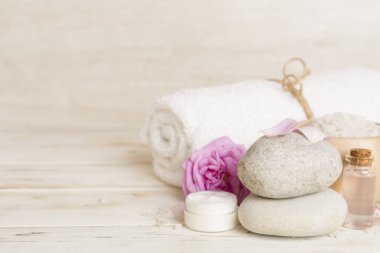 Ahşap masanın üzerinde pembe güller olan spa kompozisyonu