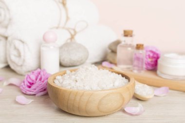 Ahşap masanın üzerinde pembe güller olan spa kompozisyonu