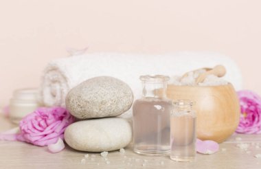 Ahşap masanın üzerinde pembe güller olan spa kompozisyonu