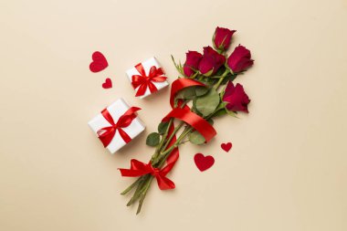 Valentines day gift box with red roses on color background, top view