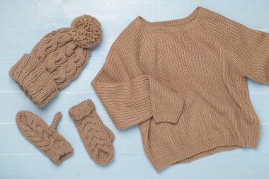 Ahşap arka planda eldivenleri olan kazak ve kış şapkası..