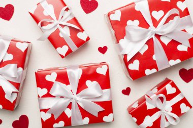 Gift boxes with hearts on concrete background, top view