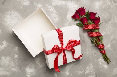 Beton zemin üzerinde kırmızı güller olan hediye kutusunu aç, üst görünüm