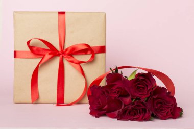 Valentines day red roses with gift on color table