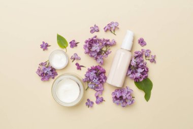 Renkli arka planda kozmetik şişeleri ve çiçekleri olan kompozisyon, üst görünüm