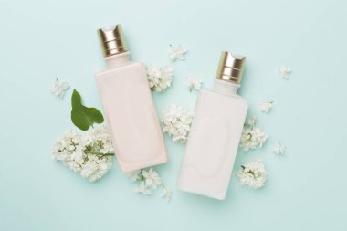 Renkli arka planda kozmetik şişesi ve çiçekli kompozisyon, üst görünüm